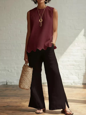 Wine red sleeveless tank top with scalloped hem, styled with black wide-leg pants and a straw bag.