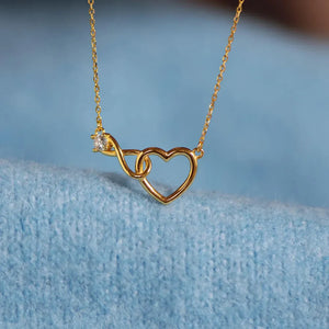 Gold necklace with intertwined heart and infinity symbol pendant featuring a cubic zirconia accent.