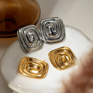 Sculpted swirl square earrings in gold and silver feature a contemporary, chic design.