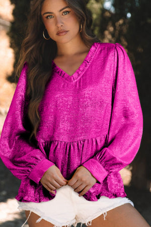 Hot pink textured satin peplum blouse with ruffled V-neck and puff sleeves.