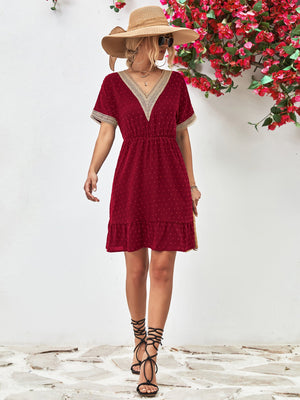 Burgundy A-line dress with Swiss dots, V-neck, crochet trim, and ruffled hem.