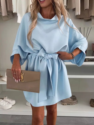 Light blue mini dress with batwing sleeves, a tie waist, and a cowl neck.
