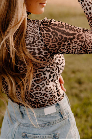 Sheer leopard print turtleneck top with long sleeves, styled with light wash denim.