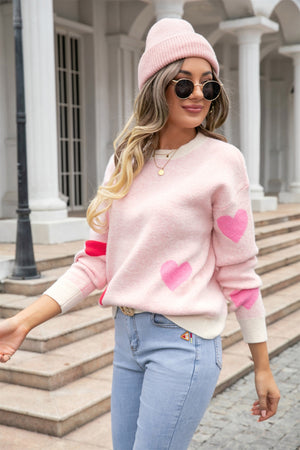 Blush pink intarsia knit crewneck sweater with heart pattern and cream trim.