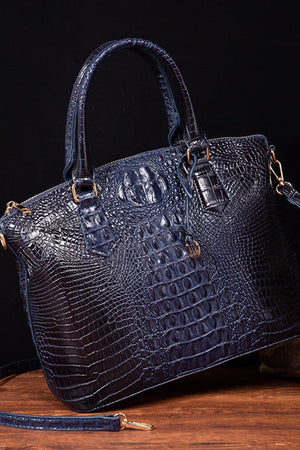 Dark blue crocodile embossed satchel with shoulder strap and gold hardware.