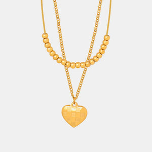 Gold layered necklace with beaded chains and a checkered heart charm.