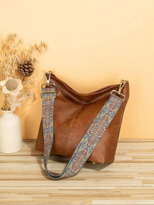 Tan pu leather crossbody bag with a colorful geometric strap and gold hardware.