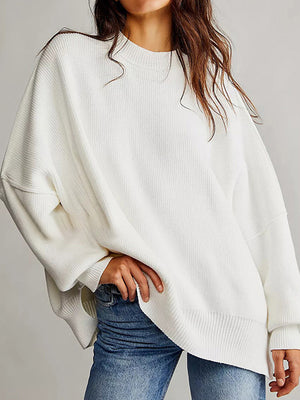 White oversized ribbed knit sweater with drop shoulders and crew neck, styled with jeans.