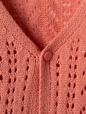 Chevron knit cardigan in burnt coral with openwork detail and button closure.