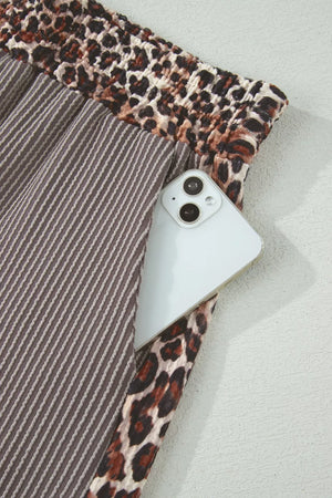 Brown ribbed knit pants with leopard print trim and a phone in the pocket.