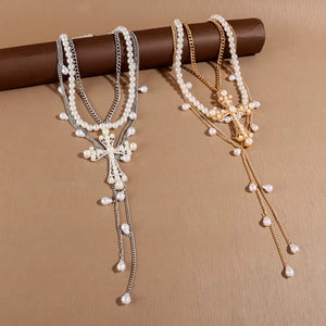 Lustrous pearl cross pendant necklaces in silver and gold with dangling pearls.