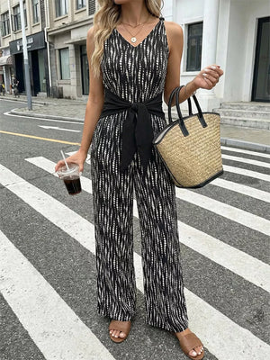 Chic tied waist wide-leg jumpsuit in black with abstract white pattern, V-neck, sleeveless, full length.