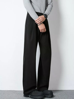 Men's black wide-leg pleated trousers with a relaxed fit.