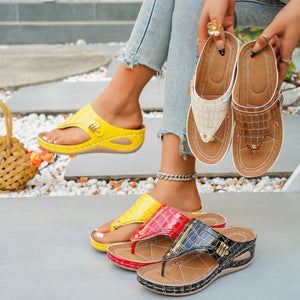 Crocodile-embossed wedge sandals in yellow, red, brown, beige, and black with thong strap and buckle detail.