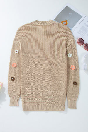 Khaki knit sweater with embroidered floral details on the sleeves.
