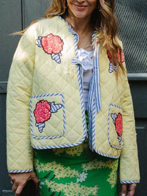 Quilted pastel yellow jacket with floral appliqué and blue trim.