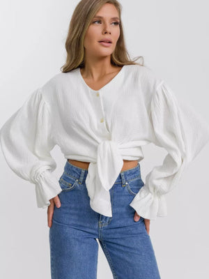 White textured puff sleeve blouse with tie front and ruffled cuffs.