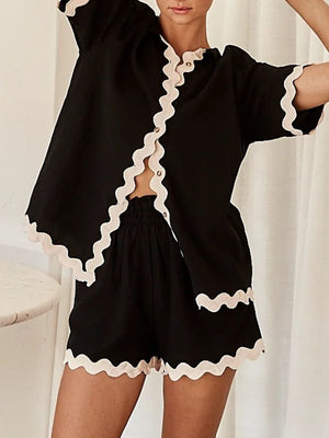 Black loungewear set with scalloped trim on short sleeves, neckline, and shorts.
