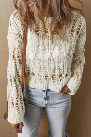 Ivory open-knit crochet crop sweater with a diamond pattern and a white tank top underneath.