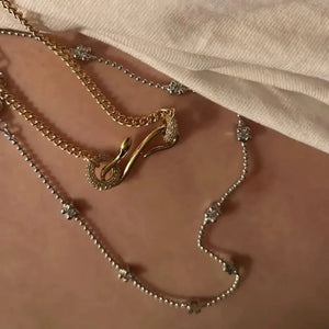 Gold curb chain necklace with serpentine zirconia clasp and silver chain with floral charms.