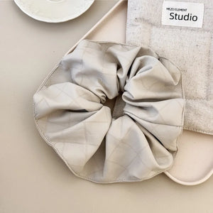 Quilted faux leather scrunchie in beige with diamond stitching detail.