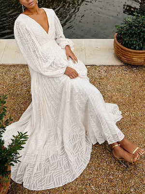 White maxi dress with V-neck, balloon sleeves, and leaf pattern fabric.