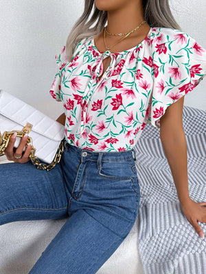 White floral ruffle sleeve tie-neck blouse with pink flowers and green leaves.