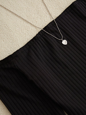 Black ribbed pencil skirt with a silver heart pendant necklace