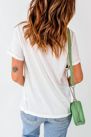 White graphic tee with rolled sleeves and a subtle eye tattoo on the arm.