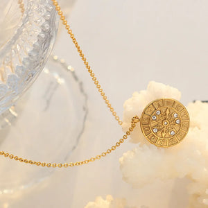 Gold zodiac compass pendant necklace with celestial details and clear stones.