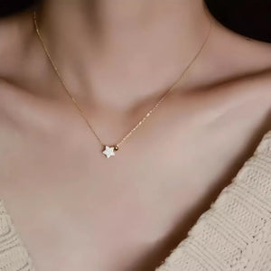 Gold necklace with a sparkling star pendant and a small bead detail.