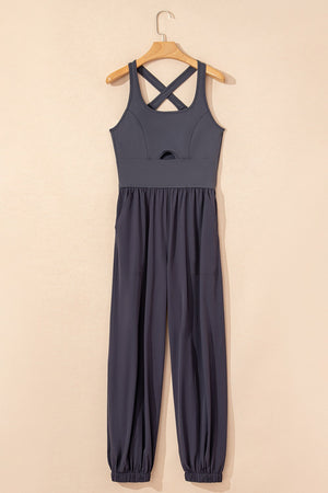 Dark gray cutout bodice jumpsuit with crisscross straps and gathered, cuffed legs.
