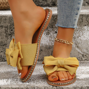 Yellow bowknot slide sandals with beaded trim.