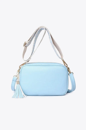 Sky blue textured crossbody bag with tassel detail and patterned strap