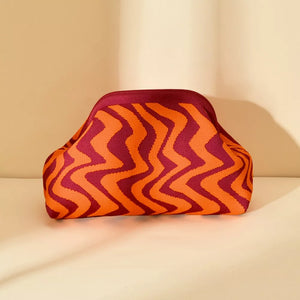 Vibrant knit clutch bag with striking orange and burgundy zig-zag stripes.