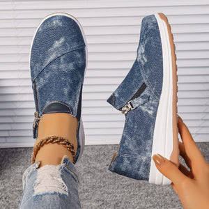 Blue denim slip-on sneakers with side zippers and a chunky white sole.