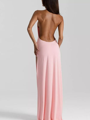 Pink ruched halter neck maxi dress with a low open back and thigh-high slit.