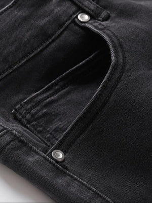 Black wash denim jeans with split hem detail and button closure.