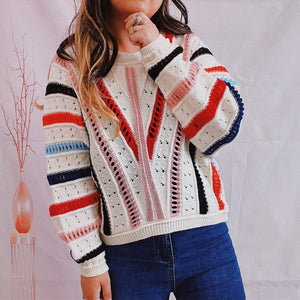 Colorblock openwork knit sweater with V-shaped stripes in red, pink, and black on a white base.