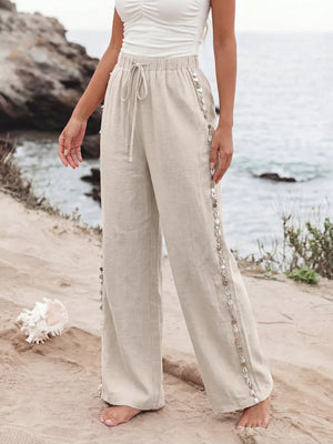 Relaxed beige drawstring wide-leg trousers with shell embellishments on the side seams.