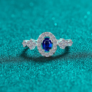 Silver oval sapphire halo ring with diamond cluster accents.