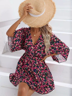 Black floral mini dress with V-neck, flutter sleeves, and ruffle hem.