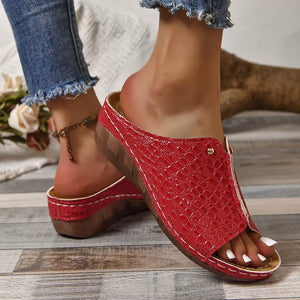 Red glossy crocodile-embossed wedge sandals with open toe and white stitching.