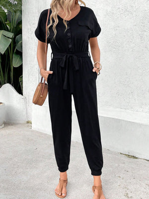 Black utility jumpsuit with short sleeves, V-neck, button front, tie waist, and pockets.
