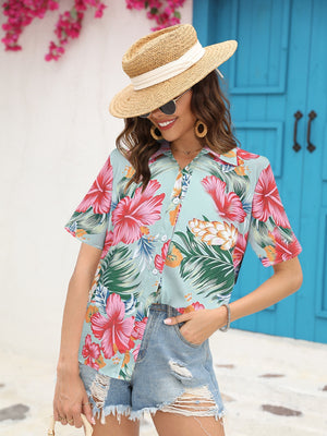 Tropical print camp collar shirt in sky blue with short sleeves and button front, styled with denim shorts.