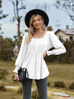 White peplum blouse with gathered yoke and smocked cuffs.
