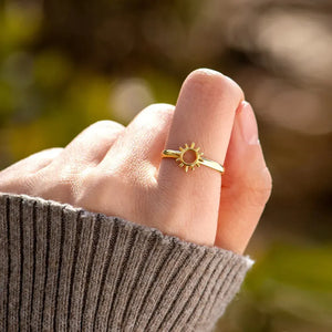 Gold sunburst signet ring with open center detail on finger.