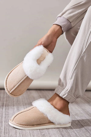 Beige suede house slides with white shearling trim and decorative stitching.