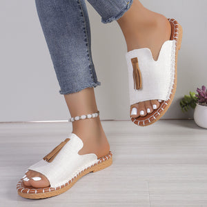 White open-toe slide sandals with tassel detail and decorative stitching