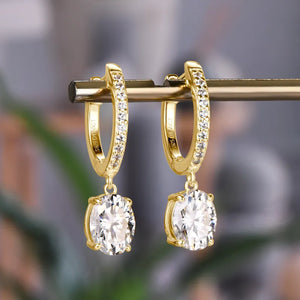Gold pavé hoop and oval moissanite drop earrings with clear stones.